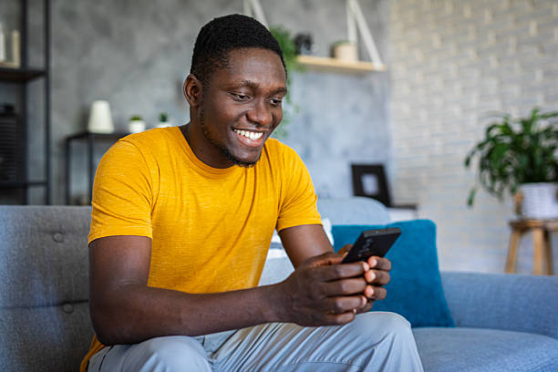 istock Young happy man using his smartphone while relaxing in  sofa at home 2233163283