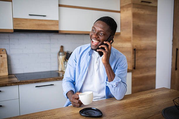 istock Cozy morning – cheerful man with coffee chatting on phone in kitchen 2233163522
