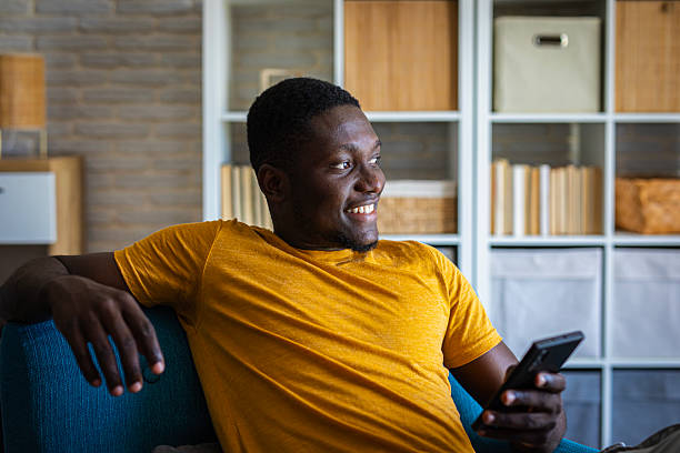 istock Young happy man using his smartphone while relaxing in  sofa at home 2233163950