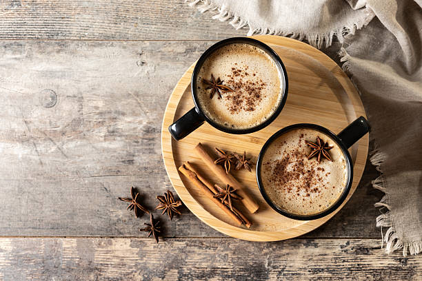 Chai Latte in Black Mug with Spices( star anise and cinnamon) on wooden table