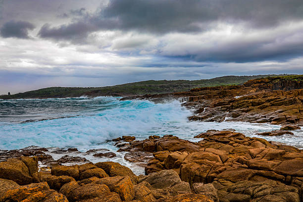 istock Powerful waves crashing against a rugged rocky coastline beneath a dramatic cloudy sky 2233165469