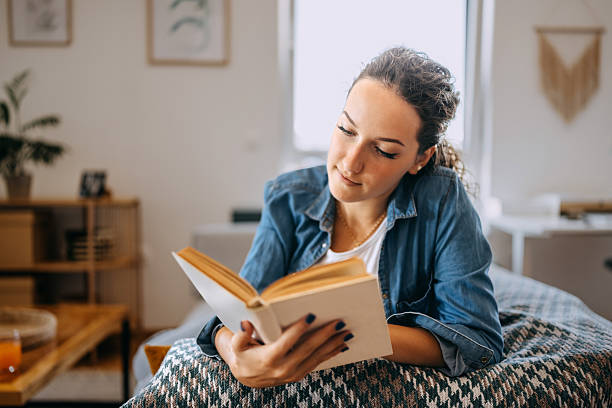 istock Young woman relaxing on sofa at home and reading book 2233166091