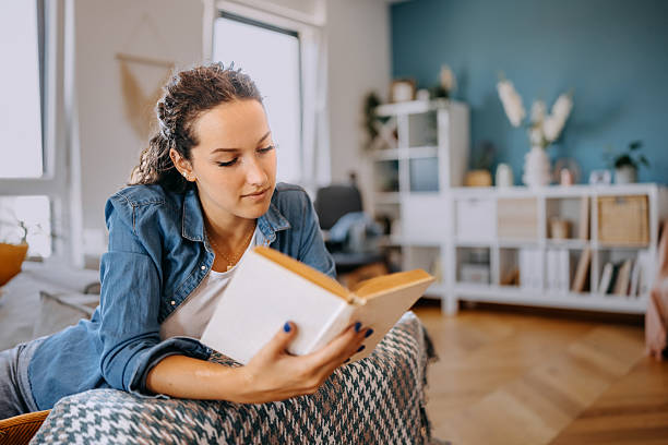 istock Young woman relaxing on sofa at home and reading book 2233166315