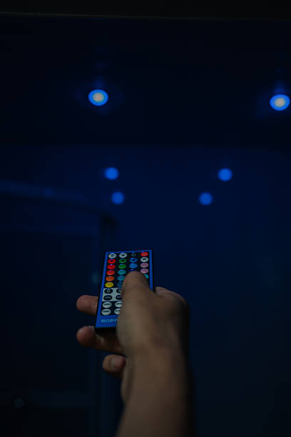 istock Close-up hand holding RGB remote control, poised to adjust smart lighting system, changing ambiance of room or setting specific mood with colorful led lights. 2233166384