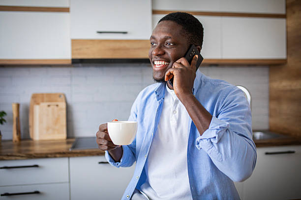 istock Cozy morning – cheerful man with coffee chatting on phone in kitchen 2233168925
