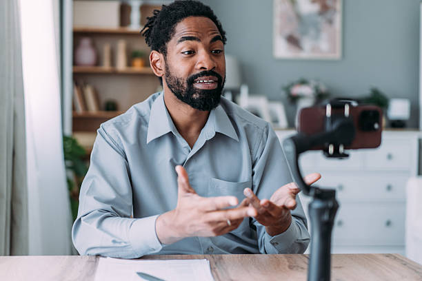 istock Young male content creator using smartphone to record vlog at home. 2233169256