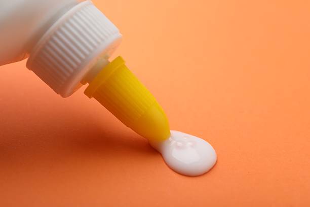 istock Applying glue from bottle on orange background, closeup. Space for text 2233173213