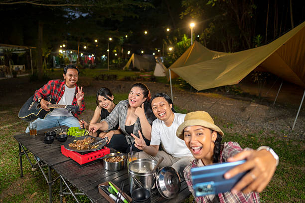 istock Indonesian southeast asian people capture a selfie while cooking sliced marinated beef bulgogi. One of them is holding an acoustic guitar. Scene of the lifestyle of enjoying food in a natural setting 2233176272