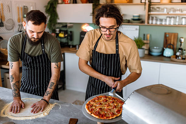 istock Two friends having fun, making pizza in domestic kitchen. 2233176443