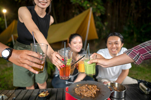 istock Indonesian southeast asian people relaxing together outdoors and enjoying refreshing drinks while cooking sliced beef on a grill pan. The scene of the lifestyle of enjoying food in a natural setting 2233176988