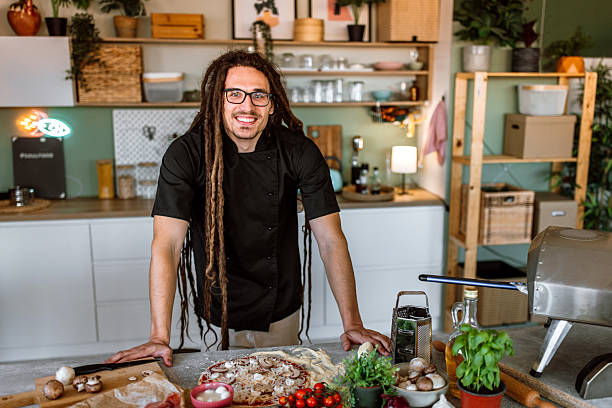 istock Portrait of a young chef with dreadlocks in kitchen, smiling looking at camera. 2233177021