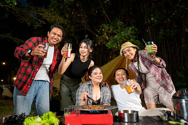 istock Indonesian southeast asian people relaxing together outdoors and enjoying refreshing drinks while cooking sliced beef on a grill pan. The scene of the lifestyle of enjoying food in a natural setting 2233177024