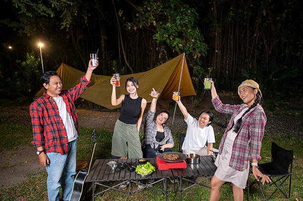 istock Indonesian southeast asian people relaxing together outdoors and enjoying refreshing drinks while cooking sliced beef on a grill pan. The scene of the lifestyle of enjoying food in a natural setting 2233177091