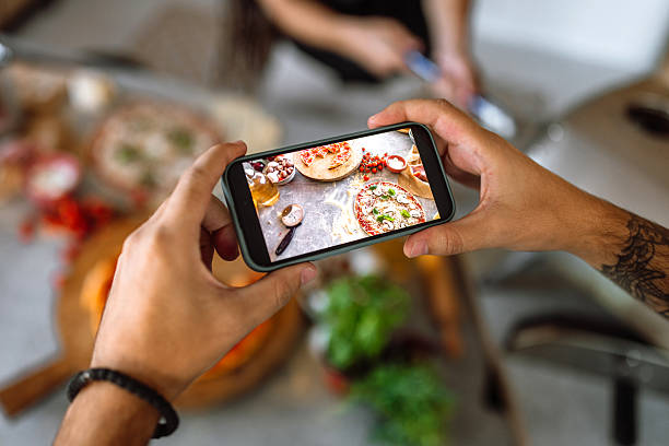 istock Two friends having fun, making and photographing pizza in domestic kitchen. 2233177143