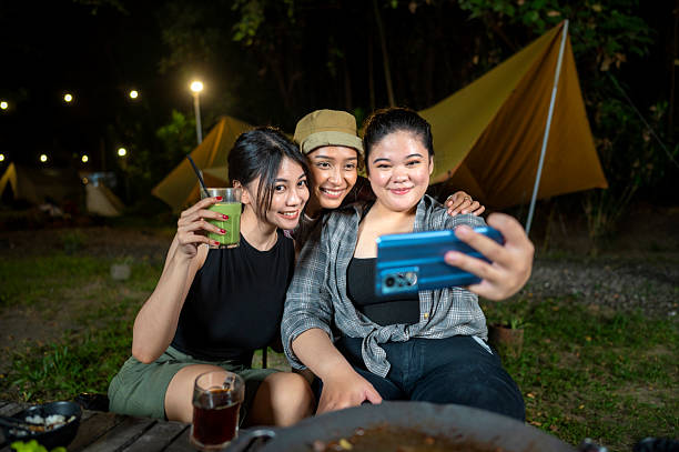 istock Indonesian southeast asian women capturing a selfie using a cellphone together outdoors and enjoying refreshing drinks. The scene of the lifestyle of enjoying food in a natural setting 2233177268