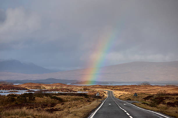 Rainbow over the empty road near Glencoe, Scotland, UK