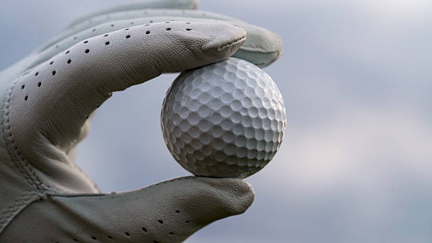 istock Close-Up Image of a Hand Holding a Golf Ball Against a Cloudy Sky 2233178109