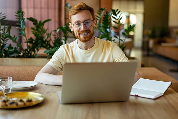 istock Ginger man professional using laptop at restaurant with pizza 2233181880