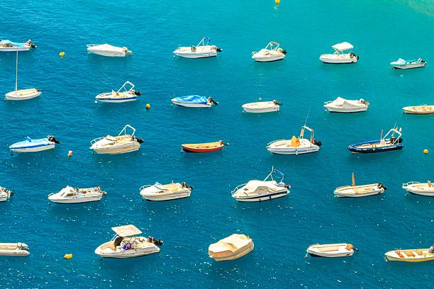 Aerial view of numerous boats floating on vibrant blue water, creating a serene and picturesque scene.