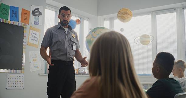 istock Male Policeman Giving Lecture to Curious Primary School Students About Safety Rules 2233183099