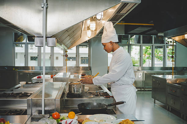 istock Culinary student practicing cooking skills with pot and ingredients in modern training kitchen 2233186208