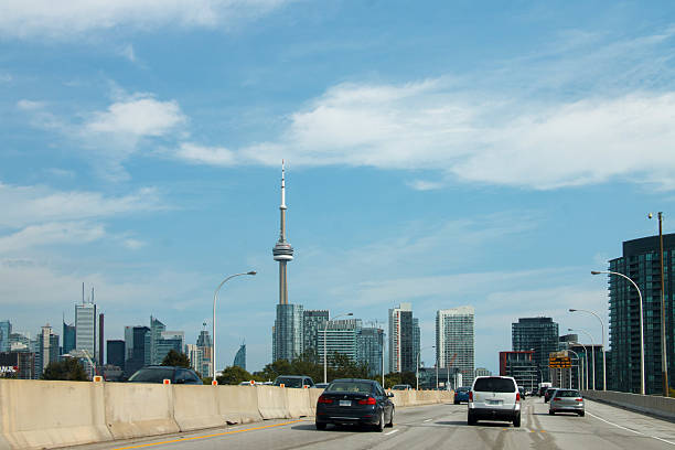 Toronto, Canada - May 26, 2024: People out and about in the intersection of Queen St. West and Spadina Street. The cityscape includes skyscrapers and the CN Tower