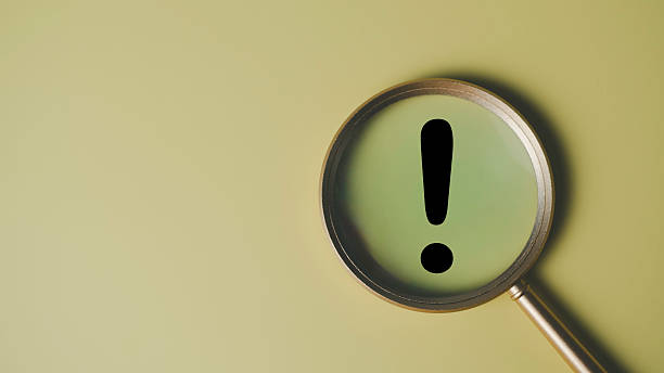 istock Warning and alert concept with magnifying glass highlighting black exclamation mark on plain background, symbolizing caution, important notice, risk awareness, and critical business message. 2233188938