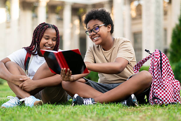 istock Two teens sitting on the grass and reading something 2233189129