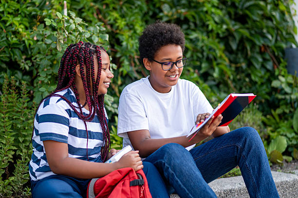 istock Two schoolkids sitting on the pavement and discussing school issues 2233189438