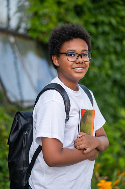 istock Dark-skinned curly-haired teen with a backpack and a book in his hands 2233189455