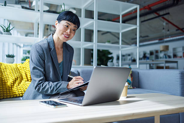 istock Businesswoman taking notes while working on laptop in modern office 2233192736