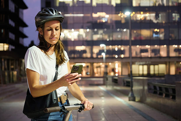 istock Young Woman Wearing Helmet Using Smartphone While Riding Electric Scooter at Night 2233194015