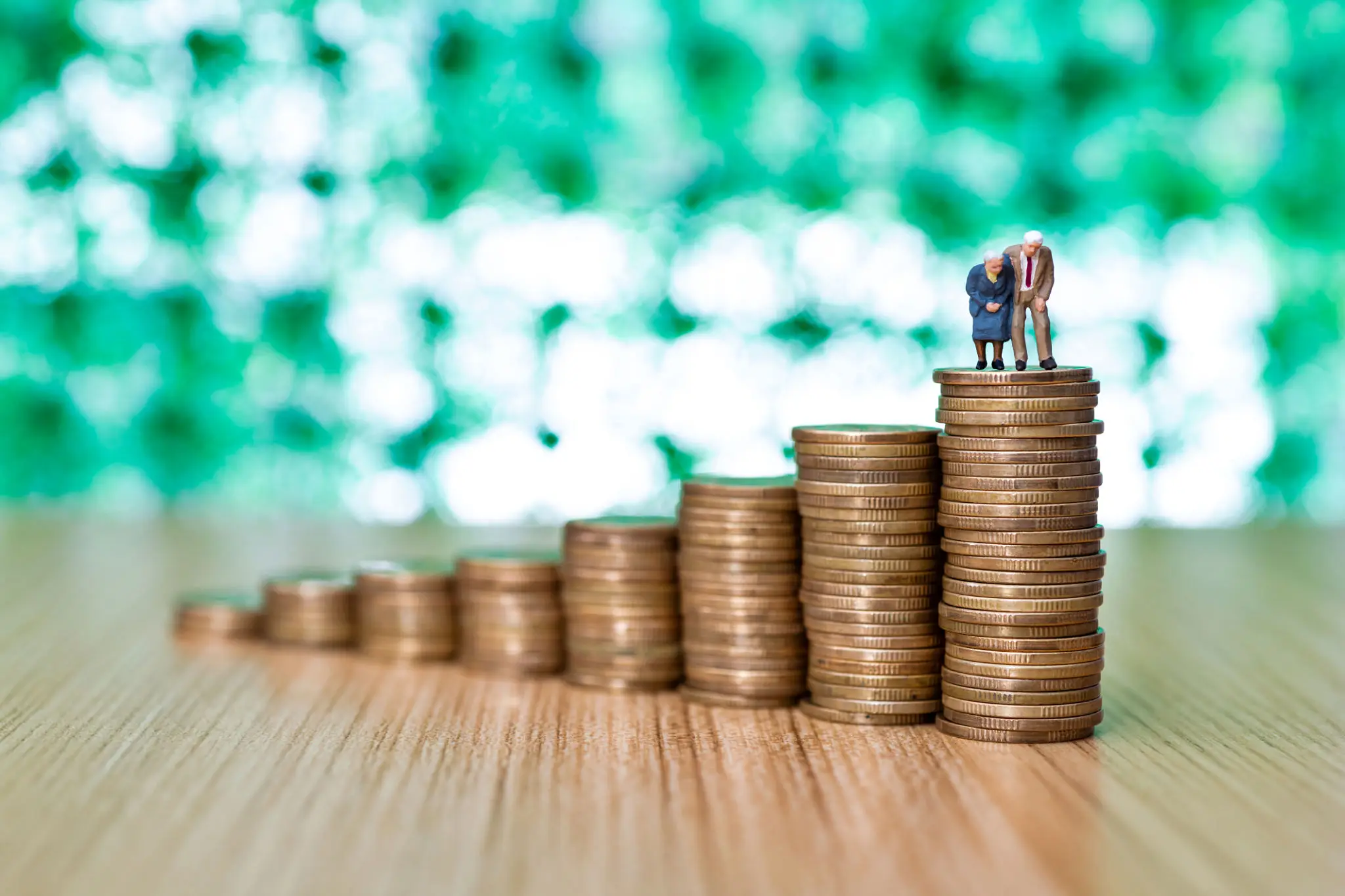 Senior figurines standing on stack of coins