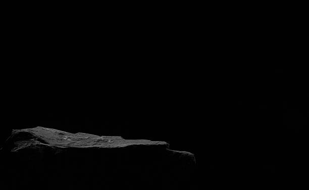 Black rock podium on dark background. Minimalist scene for cosmetic, skincare or product presentation with copy space.