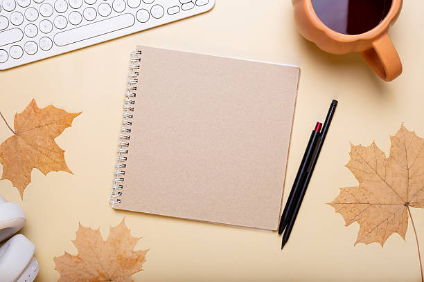 istock Autumn composition. Office desk with cup of hot tea, empty notebook, keyboard, dry leaves on beige background. Autumn, fall business concept. Flat lay, top view, copy space 2233200052