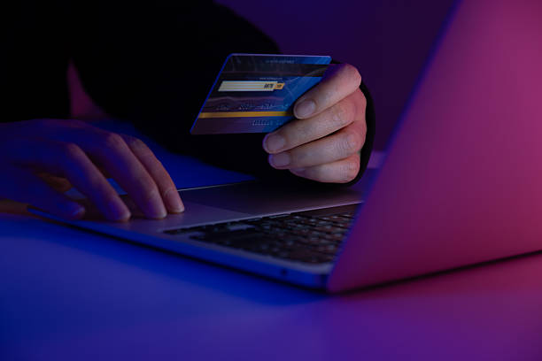 istock Hacker holding a credit card while accessing a system with a laptop. Concept of cybercrime, online fraud, identity theft, hacking, and digital security risk 2233200392