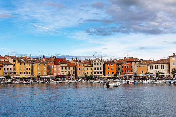 Rovinj, Croatia, August 3, 2025: A scenic view of Rovinjs vibrant old town buildings along the waterfront, with boats docked and a lively harbor atmosphere.