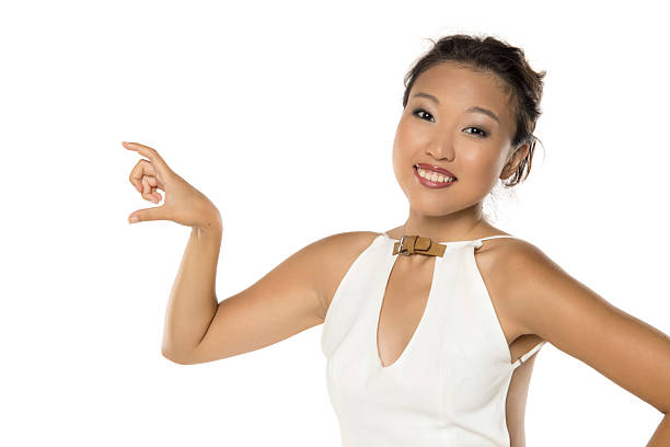Smiling Asian woman showing small size with fingers, studio shot on white background