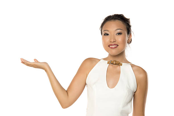 Asian woman smiling and gesturing with open hand, presenting product, studio shot on white background