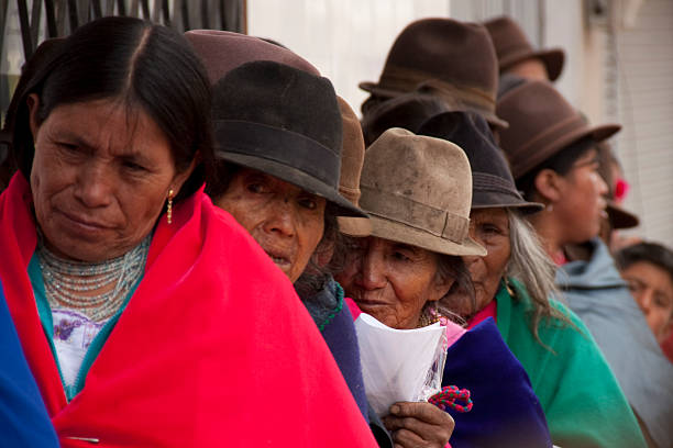 Chimborazo, Ecuador - November 4, 2012: Group of indigenous people from Chimborazo, Ecuador, wearing traditional clothes and hats, patiently waiting in line, holding a piece of paper