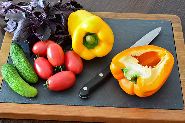 Wooden cutting board with kitchen knife and vegetables