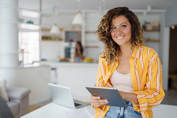 istock Smiling Woman Working from Home Holding Tablet in Bright Modern Apartment 2233213634
