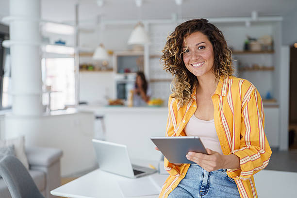 istock Young Professional Woman In Yellow Striped Blazer Using Digital Tablet In Modern Home Office Space 2233213636