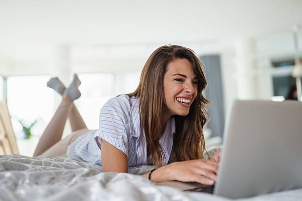 istock Smiling Young Woman Working on Laptop in Comfortable Bedroom Setting 2233216413