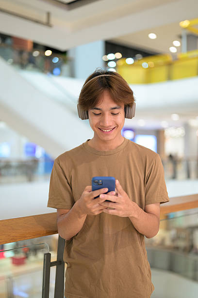istock Young Asian man texting on smartphone in shopping mall 2233219371