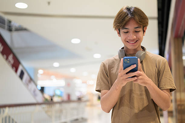 istock Young Asian man texting on smartphone in shopping mall 2233219425