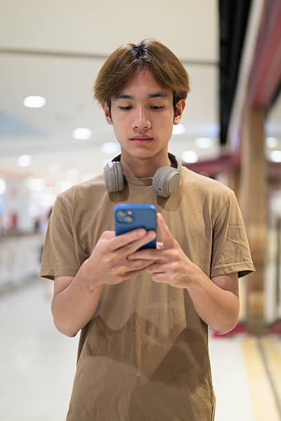 istock Young Asian man texting on smartphone in shopping mall 2233219442