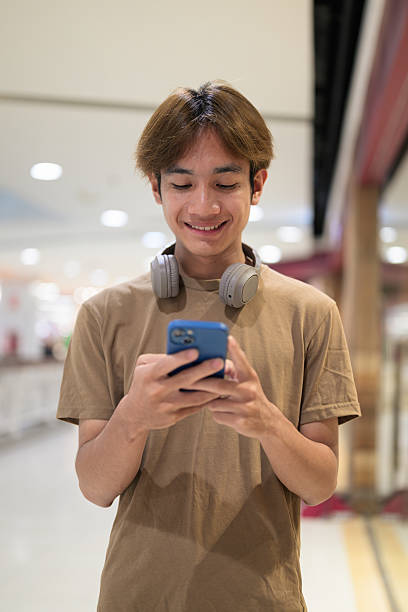 istock Young Asian man texting on smartphone in shopping mall 2233219456