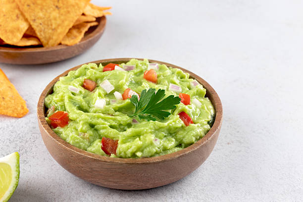istock Mexican guacamole with tomatoes, jalapenos and crispy tortilla chips on a white background. Mexican food. 2233220723