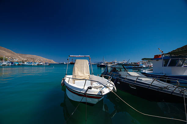 Harbor scene with boats and buildings under a clear blue sky, Kalymnos, Greece